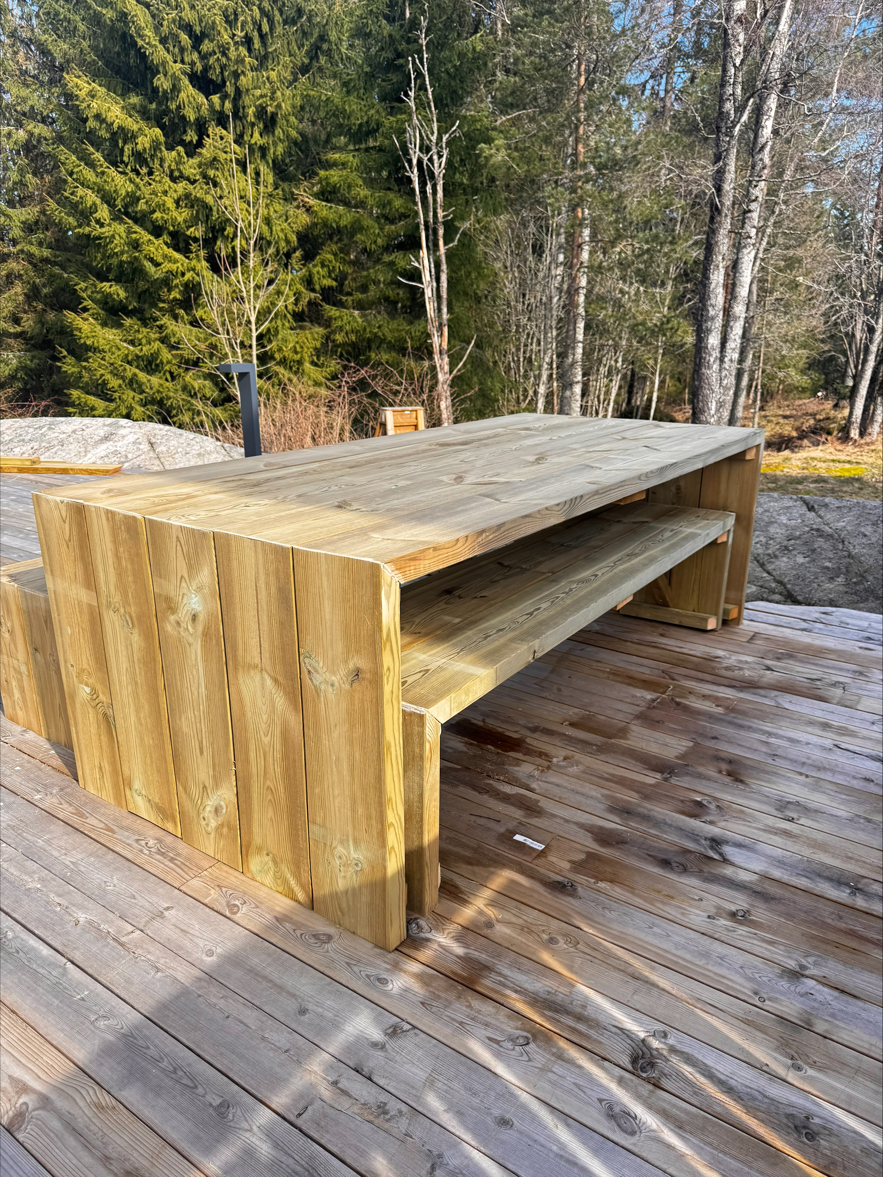 Hagebord og benk i kryssfiner på en terrasse med skog i bakgrunnen
